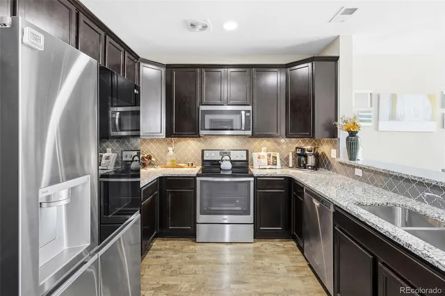 a kitchen with stainless steel appliances granite countertop a sink stove and refrigerator