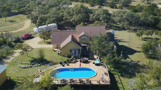 an aerial view of a house with swimming pool and lake view