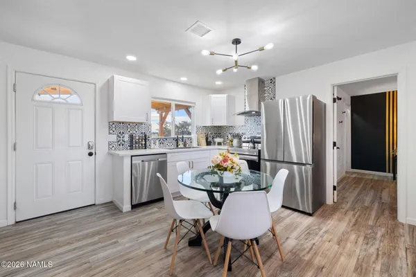 a kitchen with stainless steel appliances granite countertop a refrigerator a microwave a stove and white cabinets with wooden floor