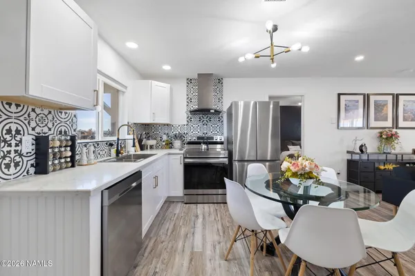 a kitchen with stainless steel appliances kitchen island granite countertop a refrigerator a stove a sink dishwasher with a dining table and chairs