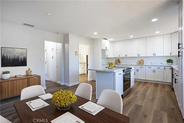 a kitchen with stainless steel appliances granite countertop a refrigerator a sink a stove top oven a dining table and chairs