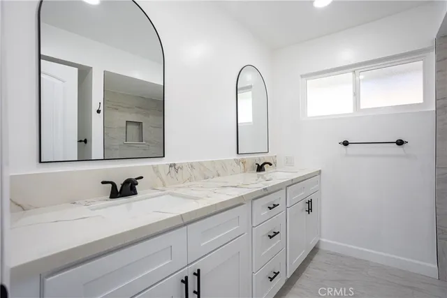 a bathroom with double vanity sink a mirror and a window