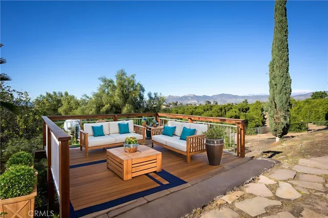 a view of a patio with couches table and chairs with wooden floor and fence