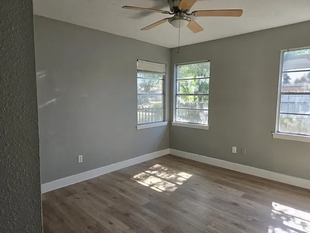a view of empty room with wooden floor and fan