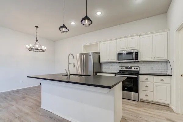 a kitchen with stainless steel appliances a sink a stove a microwave and wooden floor