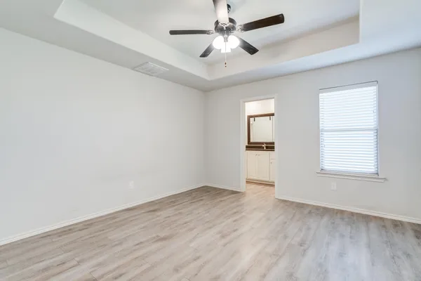 an empty room with wooden floor ceiling fan and windows