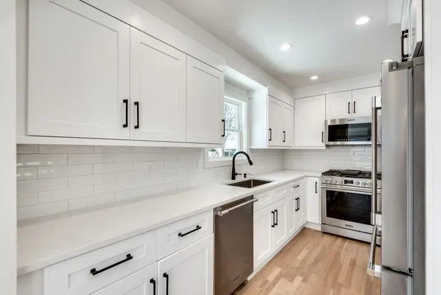a kitchen with white cabinets stainless steel appliances and sink