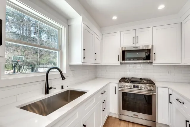 a kitchen with white cabinets a sink and a stove