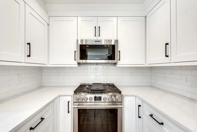 a kitchen with microwave a stove and white cabinets