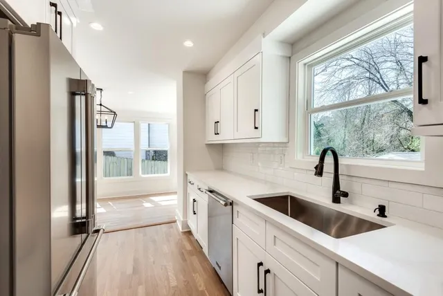 a kitchen with white cabinets and a large window