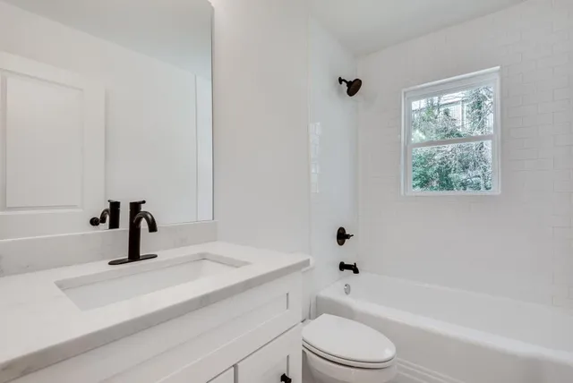 a bathroom with a granite countertop sink toilet a mirror and shower