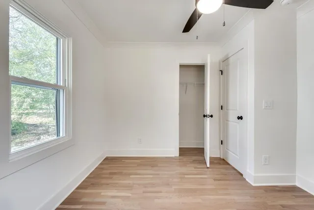 a view of an empty room with wooden floor and a window