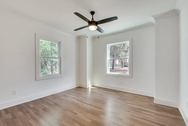 a view of an empty room with wooden floor and a window