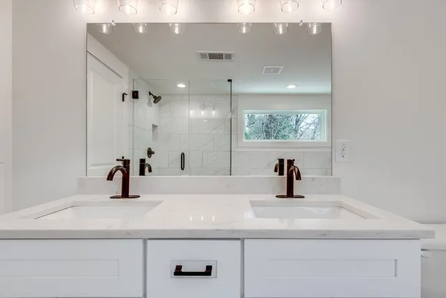 a bathroom with a double vanity sink a toilet and shower