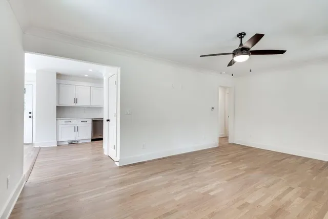 a view of empty room with wooden floor and ceiling fan