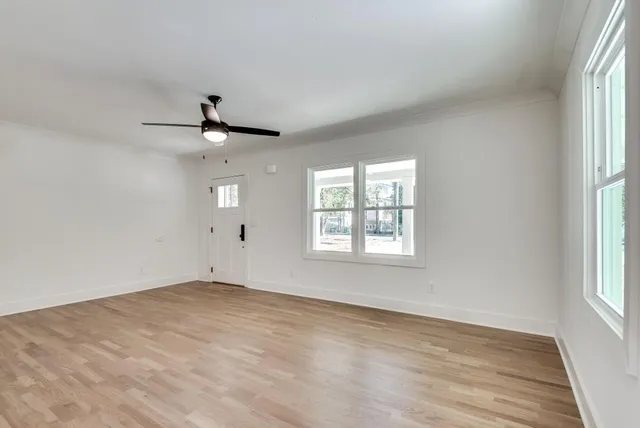 an empty room with wooden floor and windows