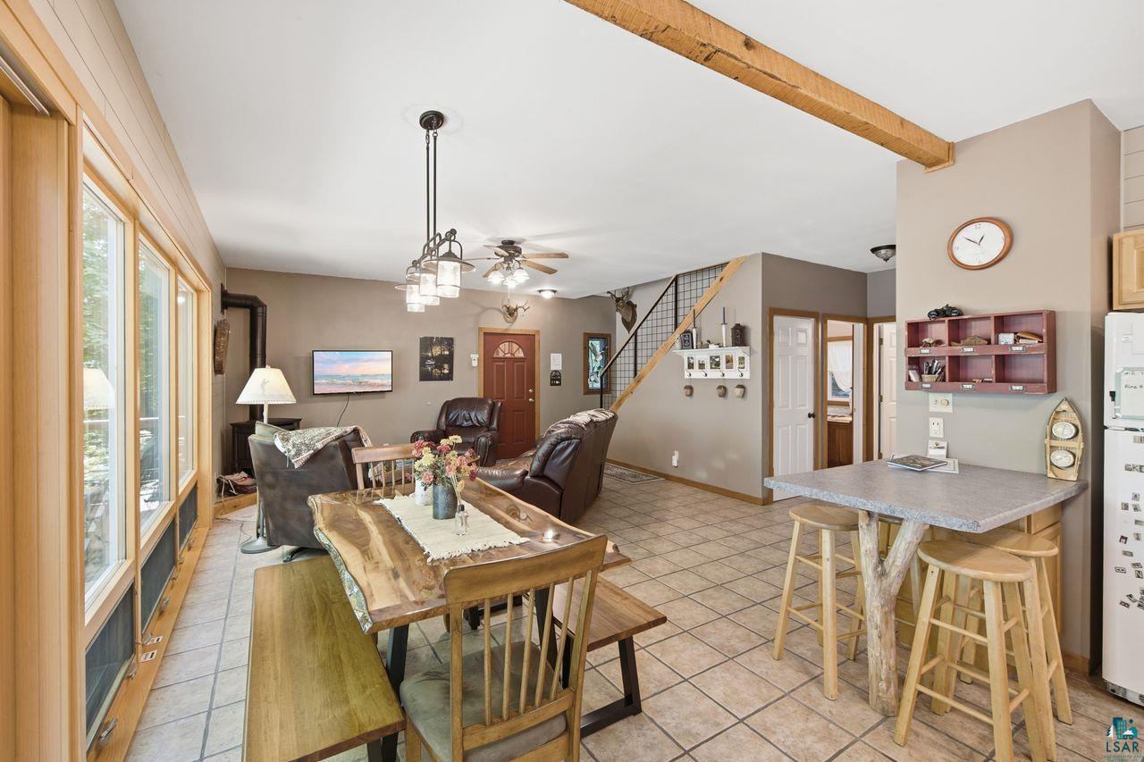 69085 East Long Lake Road Iron River, WI 54847 - Photo 14 of 33 Open-concept living area with tiled flooring, a prominent exposed wood beam, and a wood-burning stove