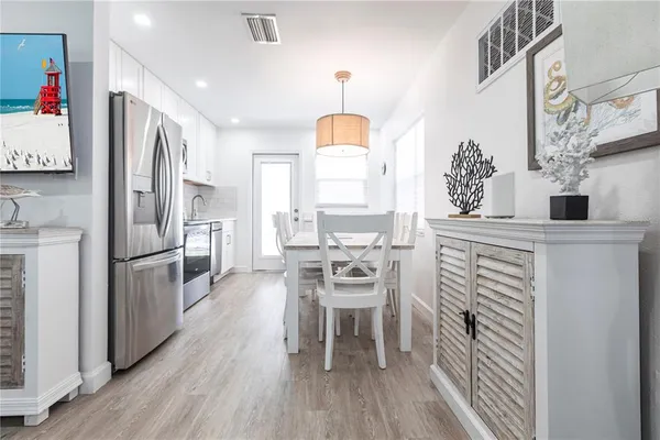 a kitchen with stainless steel appliances a refrigerator a stove a sink and white cabinets with wooden floor