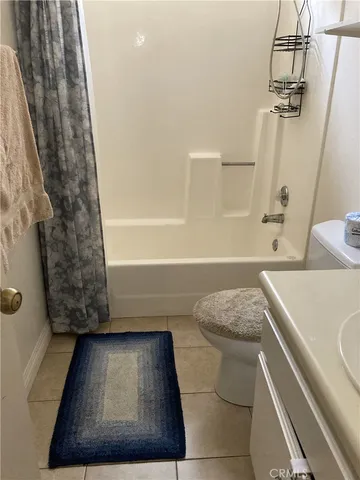a bathroom with a granite countertop bathtub shower sink vanity and toilet