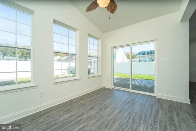 an empty room with wooden floor fan and windows