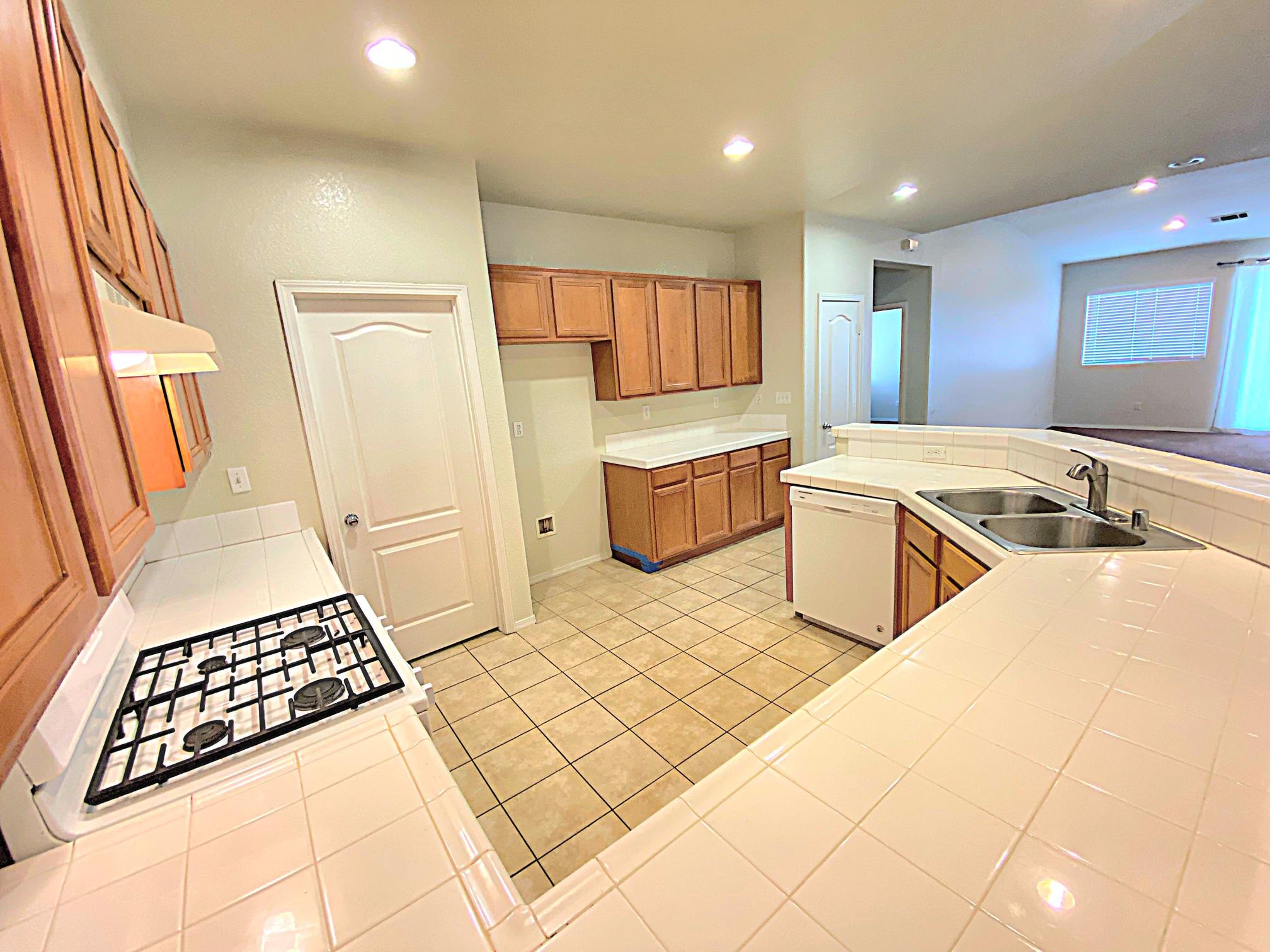 2751 Garnet Lane Lancaster, CA 93535 - Photo 22 of 46 a large white kitchen with a sink a stove a rug and a window