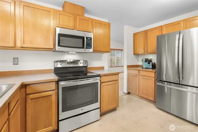 a kitchen with stainless steel appliances granite countertop a sink a stove a microwave and wooden cabinets