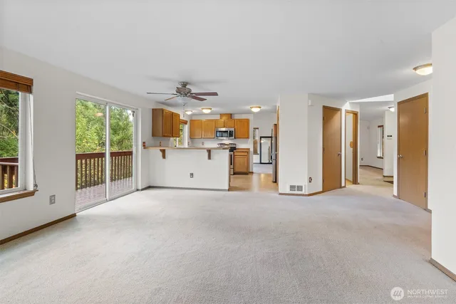 an empty room with a ceiling fan and windows