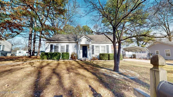 a front view of a house with a tree in front of it
