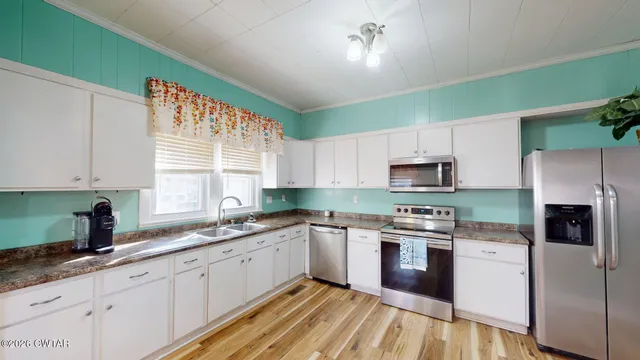 a kitchen with stainless steel appliances a sink cabinets and a window