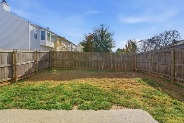a backyard of a house with large trees and wooden fence