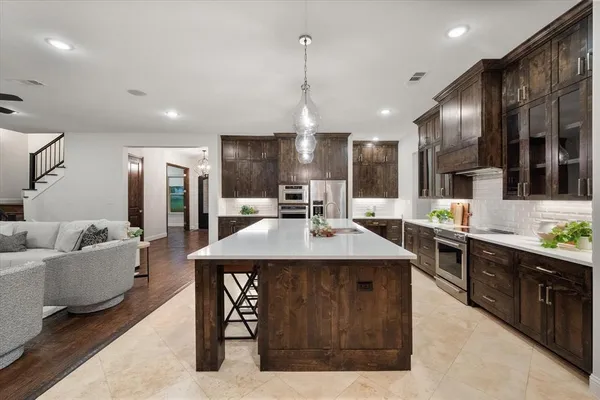 a kitchen with stainless steel appliances kitchen island granite countertop a table chairs and a refrigerator