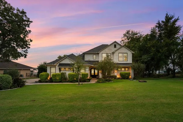 a front view of a house with a garden and trees