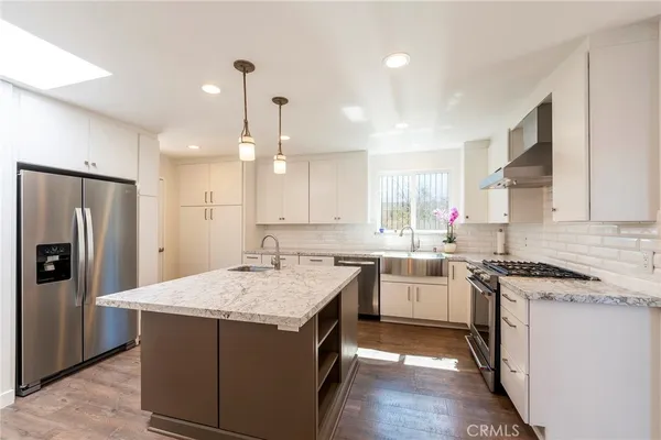 a kitchen with kitchen island granite countertop a stove and a sink