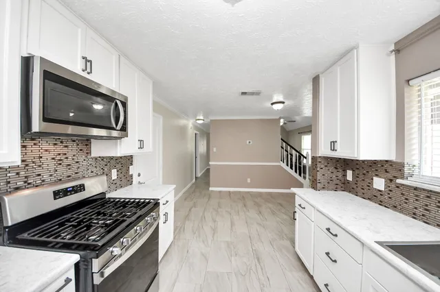 a view of an empty room with a chandelier fan