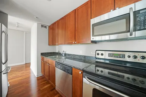 a kitchen with stainless steel appliances granite countertop a stove a sink and a microwave