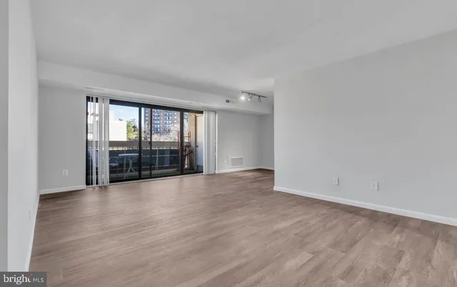 a view of an empty room with wooden floor and a fireplace