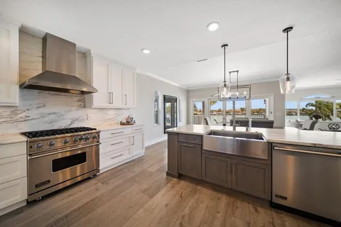 a kitchen with stainless steel appliances a stove a sink a refrigerator and a wooden floor