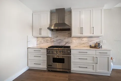 a kitchen with stainless steel appliances granite countertop a stove and a white cabinets