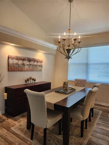 a view of a dining room with furniture a chandelier and wooden floor
