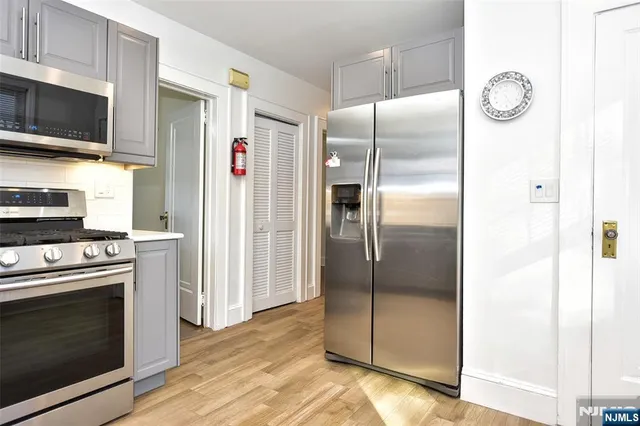 a view of an empty room with window and a refrigerator