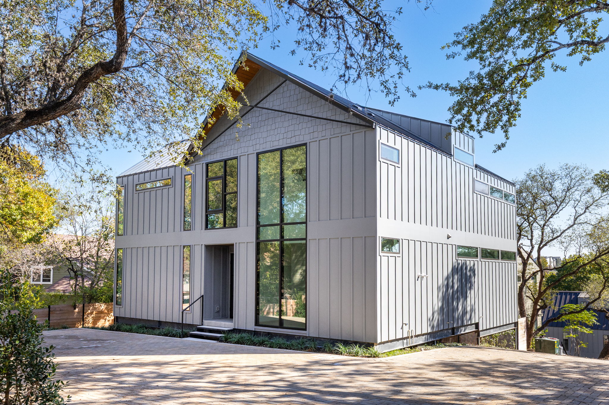 1603 Chelsea Lane, Unit 1 Austin, TX 78704 - Photo 1 of 34 Striking contemporary architecture showcases board and batten siding beneath towering mature oak trees.