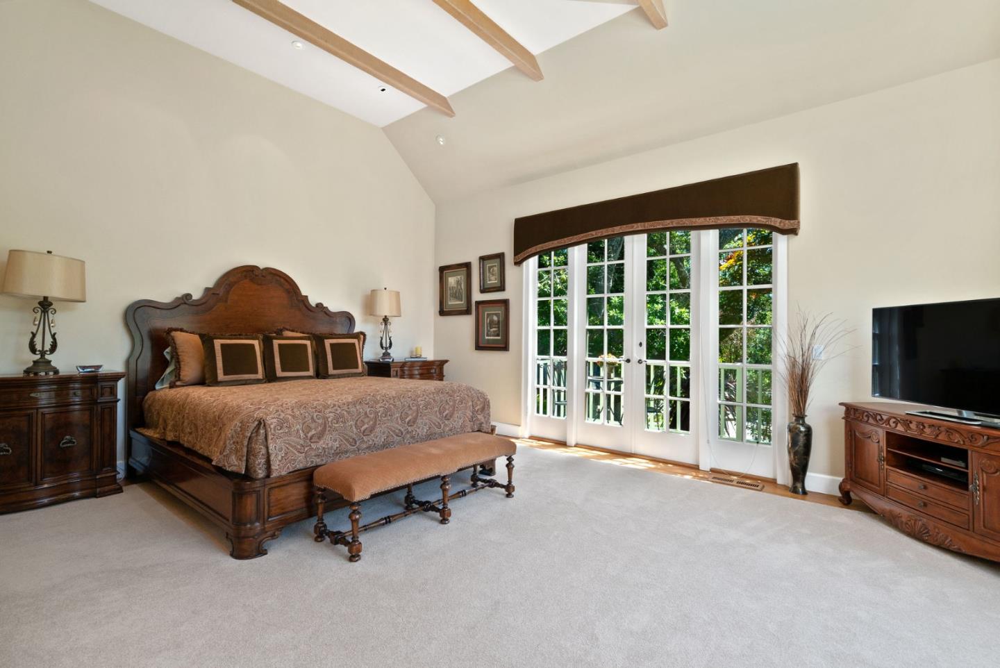 25951 Ridgewood Road Carmel, CA 93923 - Photo 16 of 32 a spacious bedroom with a bed and a flat tv screen on dresser