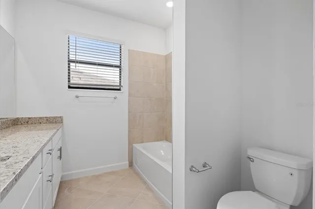 a bathroom with a granite countertop toilet a sink and bathtub