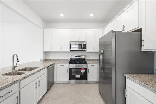 a kitchen with stainless steel appliances granite countertop a refrigerator sink and stove