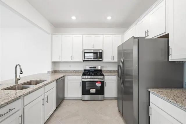 a kitchen with stainless steel appliances granite countertop a refrigerator sink and stove