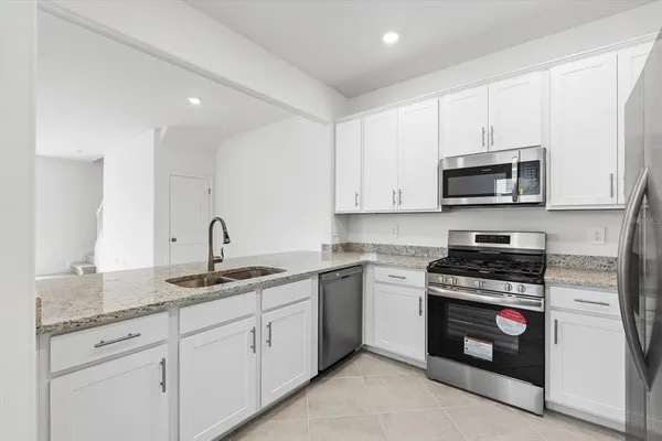 a kitchen with granite countertop white cabinets and stainless steel appliances