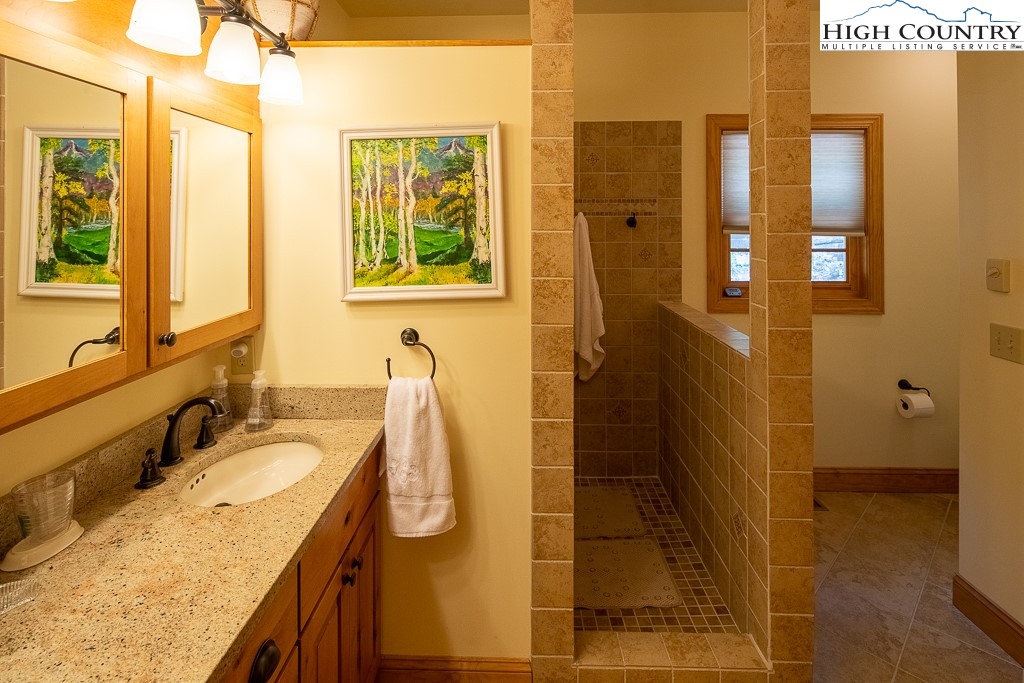 508 St Andrews Road Beech Mountain, NC 28604 - Photo 6 of 13 a bathroom with a granite countertop shower a sink and a mirror