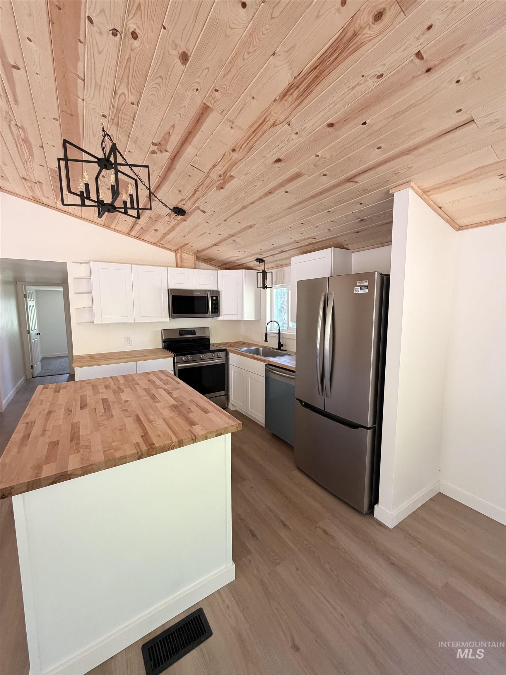 151 View Road Kamiah, ID 83536 - Photo 5 of 49 Kitchen featuring a wood-panel vaulted ceiling, white cabinetry, wood-finish countertops, stainless steel appliances, and an island with a wood-finish top