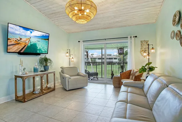 a living room with furniture a chandelier and kitchen view