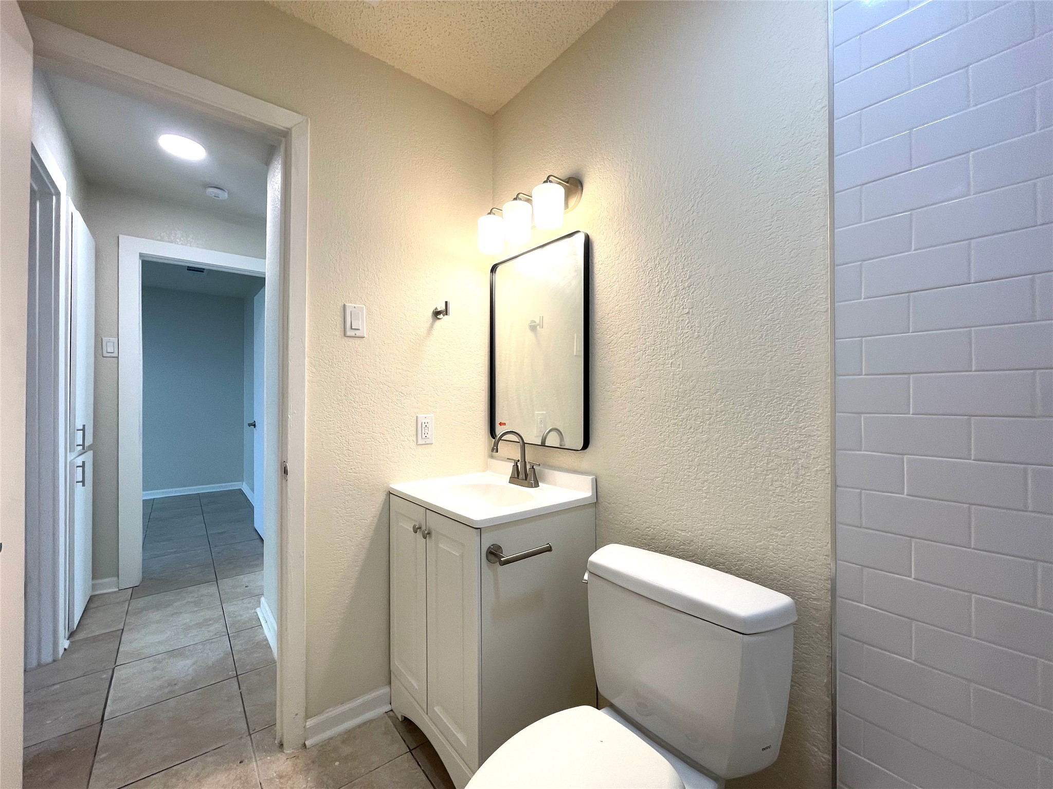 6510 Hickman Avenue, Unit 102 Austin, TX 78723 - Photo 30 of 32 Bathroom with vanity, light tile patterned floors, and a textured wall